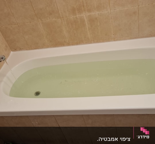 אמבטיה מלאה מים עם ברז פתוח על קיר אריחים
